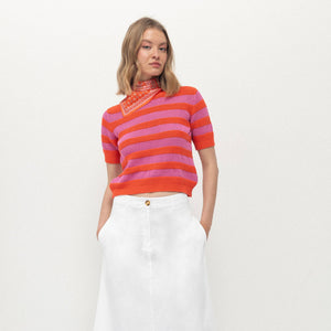 Woman wearing a colorful striped sweater and white skirt on a white background